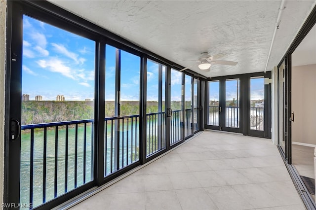 unfurnished sunroom featuring ceiling fan, a healthy amount of sunlight, and a water view