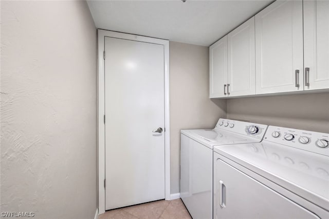 washroom featuring cabinets, washer and clothes dryer, and light tile patterned flooring