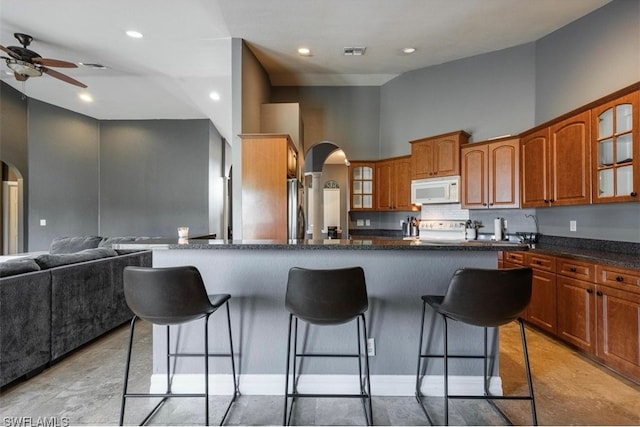 kitchen with range, ceiling fan, high vaulted ceiling, light tile floors, and a breakfast bar area