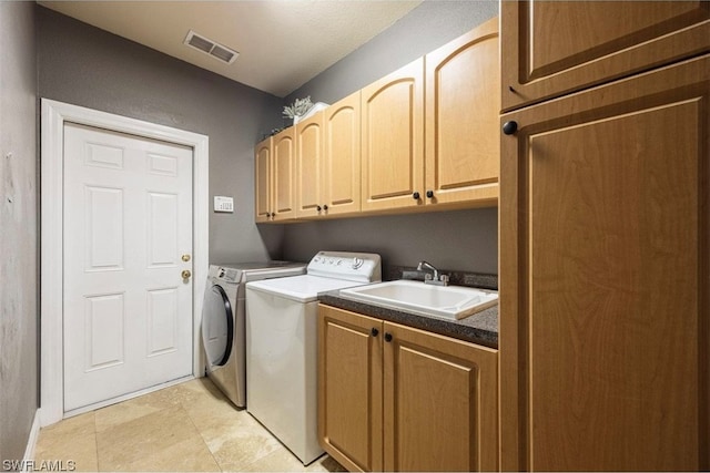 clothes washing area featuring light tile floors, cabinets, sink, and washer and clothes dryer