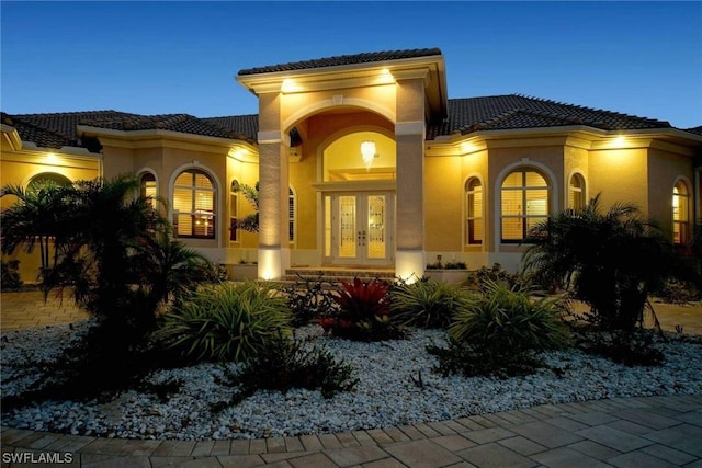 back of property featuring stucco siding, a tiled roof, and french doors