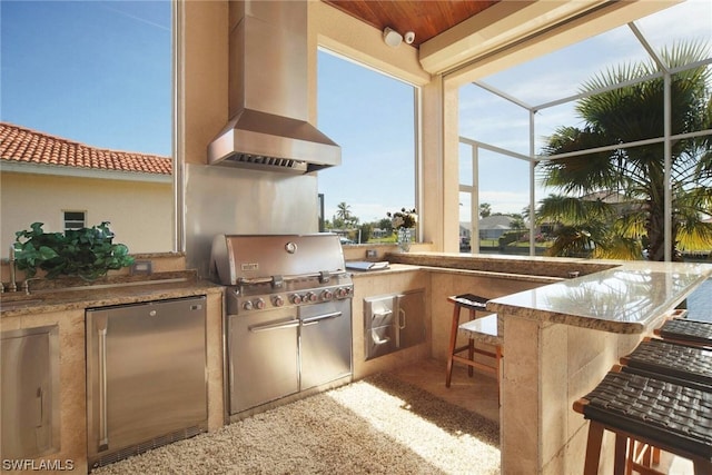 view of patio featuring glass enclosure, area for grilling, and outdoor wet bar