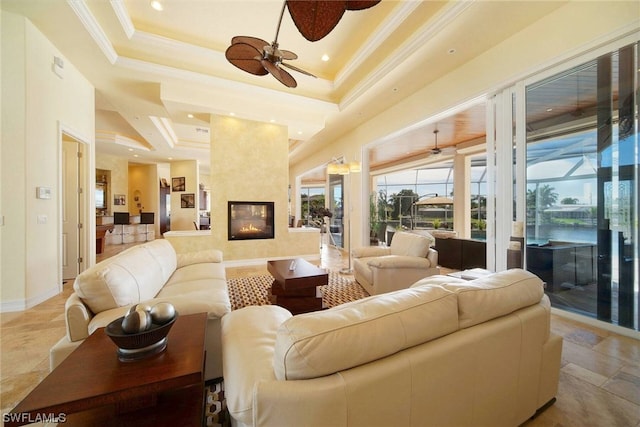 living room featuring baseboards, a fireplace, a tray ceiling, and crown molding