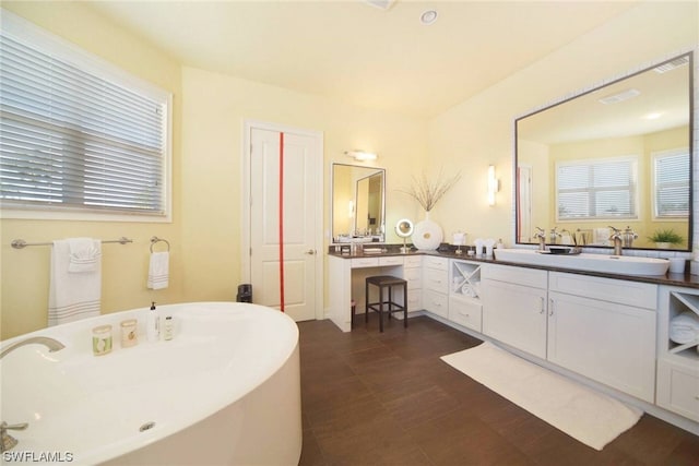 bathroom with a sink, double vanity, and a freestanding tub