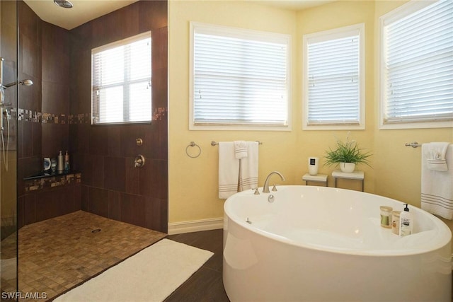 full bathroom with a freestanding bath, walk in shower, and baseboards