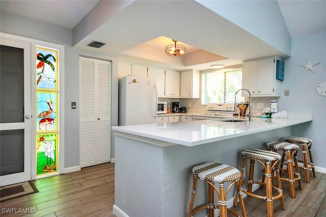 14865 Mango Ct, Captiva, FL 33924 - kitchen featuring white appliances, visible vents, wood tiled floor, a tray ceiling, and a sink