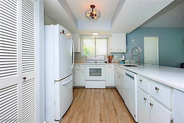 kitchen featuring white appliances, a notable chandelier, sink, white cabinetry, and light wood-type flooring