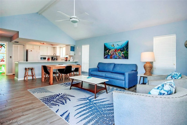 living room featuring baseboards, ceiling fan, beam ceiling, wood finished floors, and high vaulted ceiling