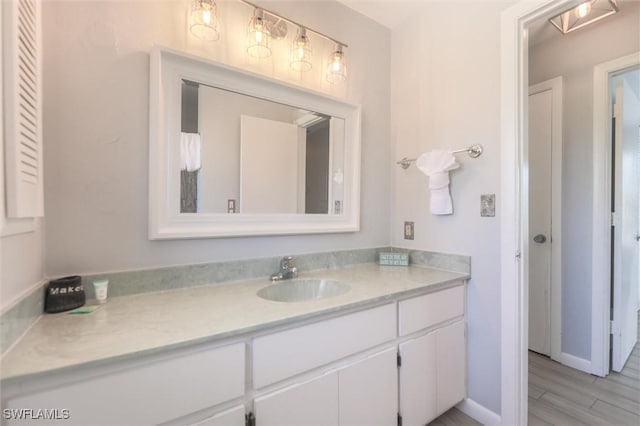 bathroom featuring baseboards, wood finished floors, and vanity