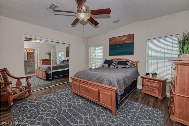 bedroom featuring a closet, lofted ceiling, ceiling fan, dark wood-type flooring, and connected bathroom