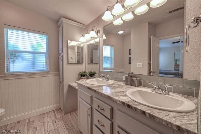 bathroom with toilet, a healthy amount of sunlight, double sink, and vanity with extensive cabinet space