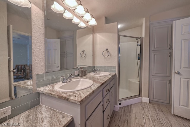 bathroom with a shower with shower door, dual sinks, a textured ceiling, large vanity, and hardwood / wood-style flooring