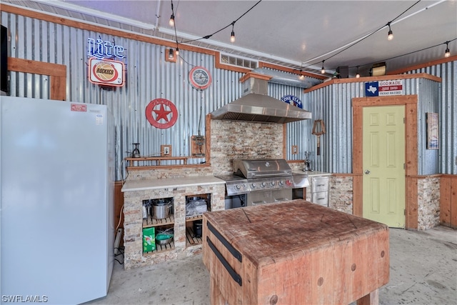 kitchen with white fridge and wall chimney range hood