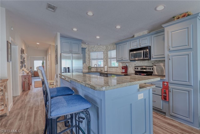 kitchen featuring backsplash, light hardwood / wood-style flooring, stainless steel appliances, and a center island