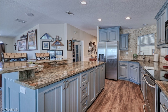 kitchen with a kitchen island, stainless steel fridge with ice dispenser, backsplash, dark stone countertops, and dark hardwood / wood-style flooring