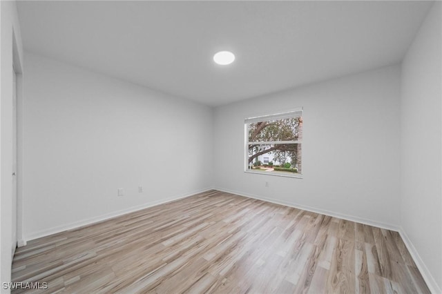 empty room with light wood finished floors and baseboards