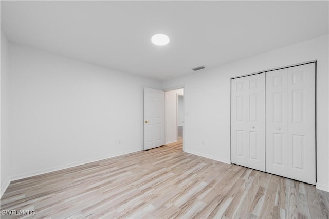 unfurnished bedroom with light wood-style floors, baseboards, visible vents, and a closet