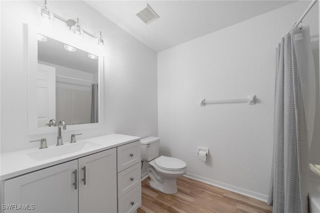 bathroom with curtained shower, toilet, wood finished floors, vanity, and visible vents