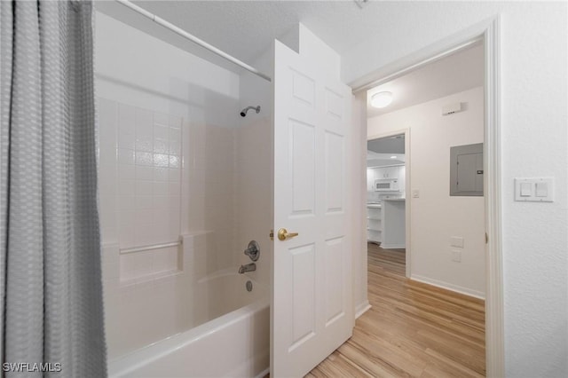 full bathroom featuring shower / tub combo, electric panel, baseboards, and wood finished floors