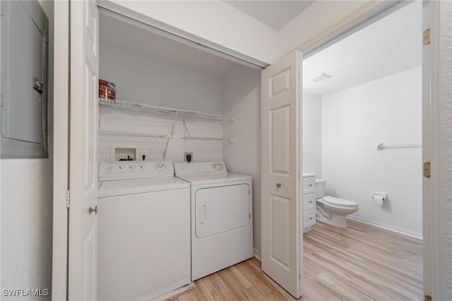 laundry area with laundry area, electric panel, light wood finished floors, and washing machine and clothes dryer