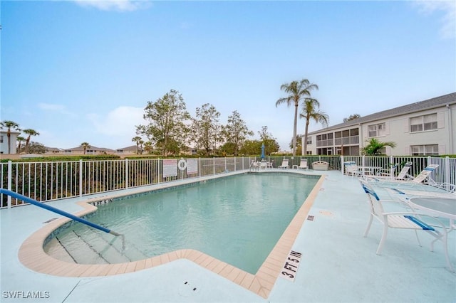 pool with a patio area and fence