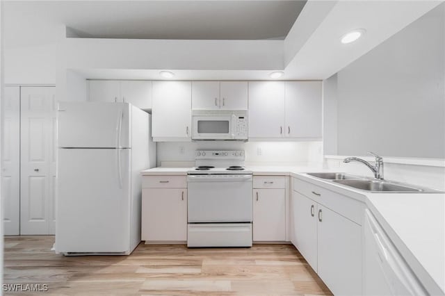 kitchen with white appliances, light countertops, a sink, and light wood finished floors