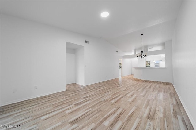 empty room featuring baseboards, visible vents, lofted ceiling, light wood-style flooring, and a notable chandelier