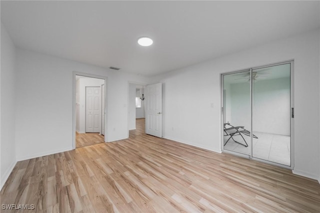 unfurnished bedroom featuring a closet, visible vents, baseboards, and wood finished floors