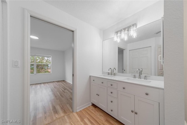 bathroom featuring double vanity, baseboards, a sink, and wood finished floors