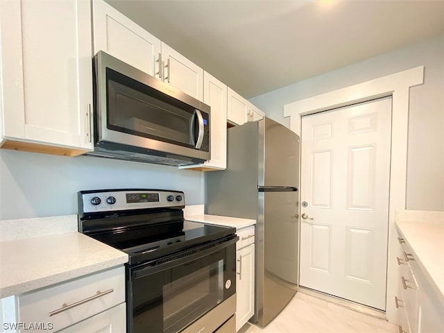 kitchen featuring white cabinets, stainless steel appliances, light tile floors, and light stone counters