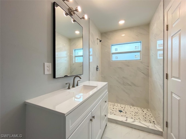 bathroom with plenty of natural light, vanity with extensive cabinet space, tile floors, and tiled shower