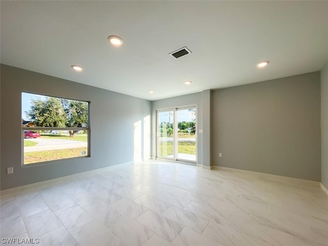 unfurnished room featuring light tile flooring and a healthy amount of sunlight