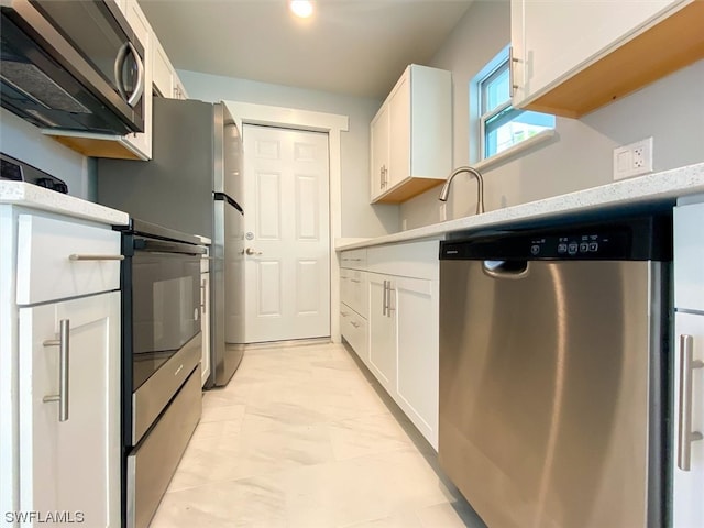 kitchen with appliances with stainless steel finishes, light tile flooring, white cabinets, and light stone countertops