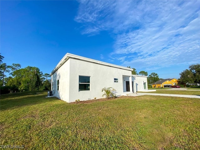 view of side of property featuring a yard and central AC