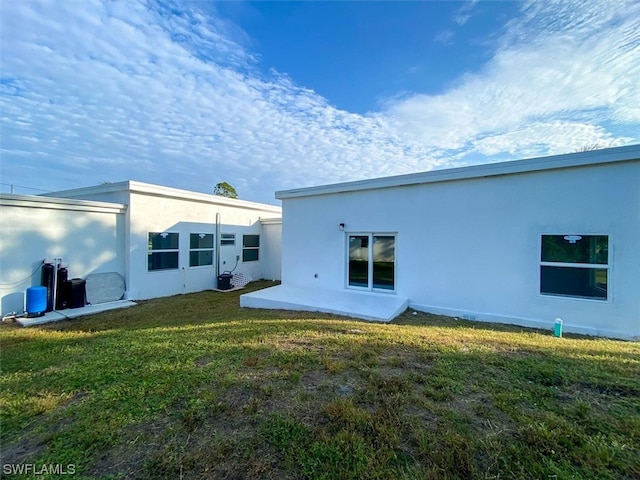 rear view of house with a lawn and a patio