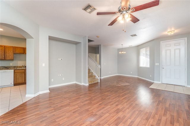 unfurnished living room with ceiling fan with notable chandelier and light hardwood / wood-style floors