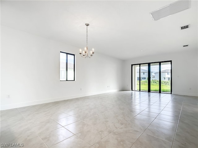 unfurnished room featuring a notable chandelier, a wealth of natural light, and light tile flooring