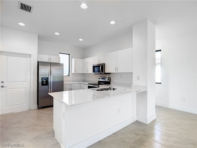 kitchen with white cabinetry, kitchen peninsula, appliances with stainless steel finishes, and light tile floors