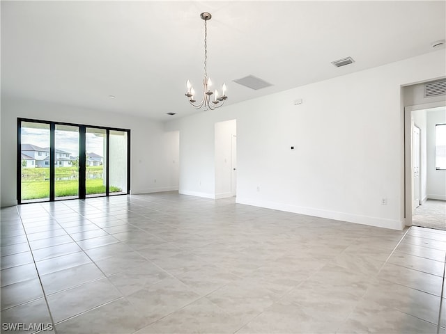 tiled empty room with an inviting chandelier