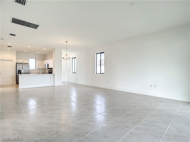 unfurnished living room featuring an inviting chandelier and light tile flooring