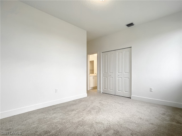 unfurnished bedroom featuring a closet and light carpet