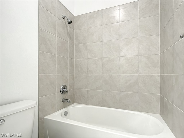 bathroom with toilet and tiled shower / bath combo