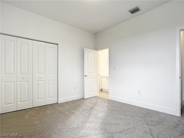 unfurnished bedroom with light carpet and a closet