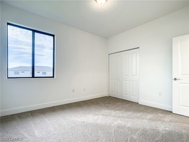 unfurnished bedroom featuring light colored carpet and a closet