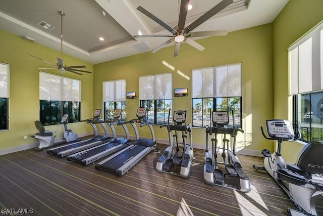 workout area with a raised ceiling, ceiling fan, and a towering ceiling