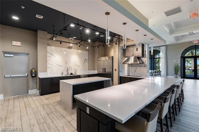 kitchen featuring built in refrigerator, light hardwood / wood-style flooring, backsplash, decorative light fixtures, and a center island