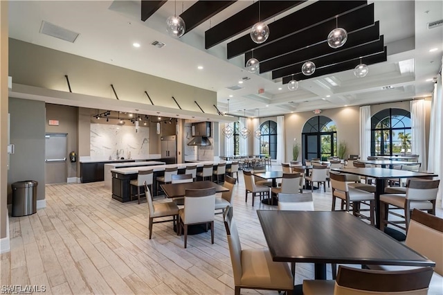 dining space featuring light hardwood / wood-style floors and beamed ceiling