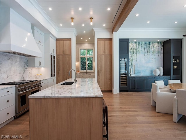 kitchen featuring light stone counters, white cabinets, light hardwood / wood-style floors, premium range hood, and range with two ovens