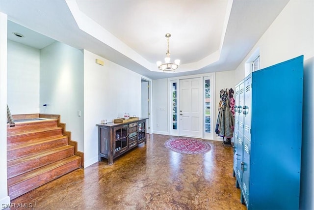 foyer entrance featuring a raised ceiling and an inviting chandelier