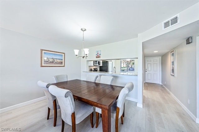 dining area with an inviting chandelier, light hardwood / wood-style floors, and sink